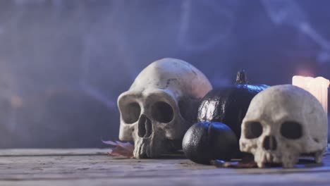 Video-of-halloween-skulls,-candle-and-smoke-with-copy-space-on-purple-background