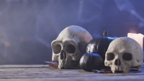 video of halloween skulls, candle and smoke with copy space on purple background