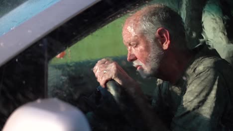 very sad man sitting in automobile dealing with depression as rain hits the windshield in slow motion