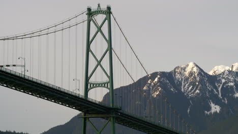 famous lions gate bridge of vancouver with snow packed mountains on background in bc, canada