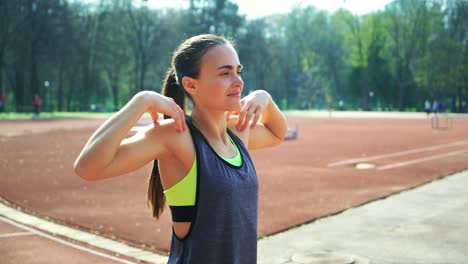 attractive woman with a beautiful slender figure doing a warm-up on the stadium running track