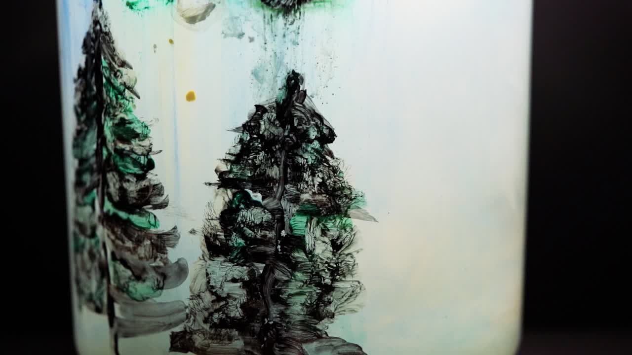 White paint floating in water tank with pine tree drawing inside. Stable shot with the Sony a7iii.