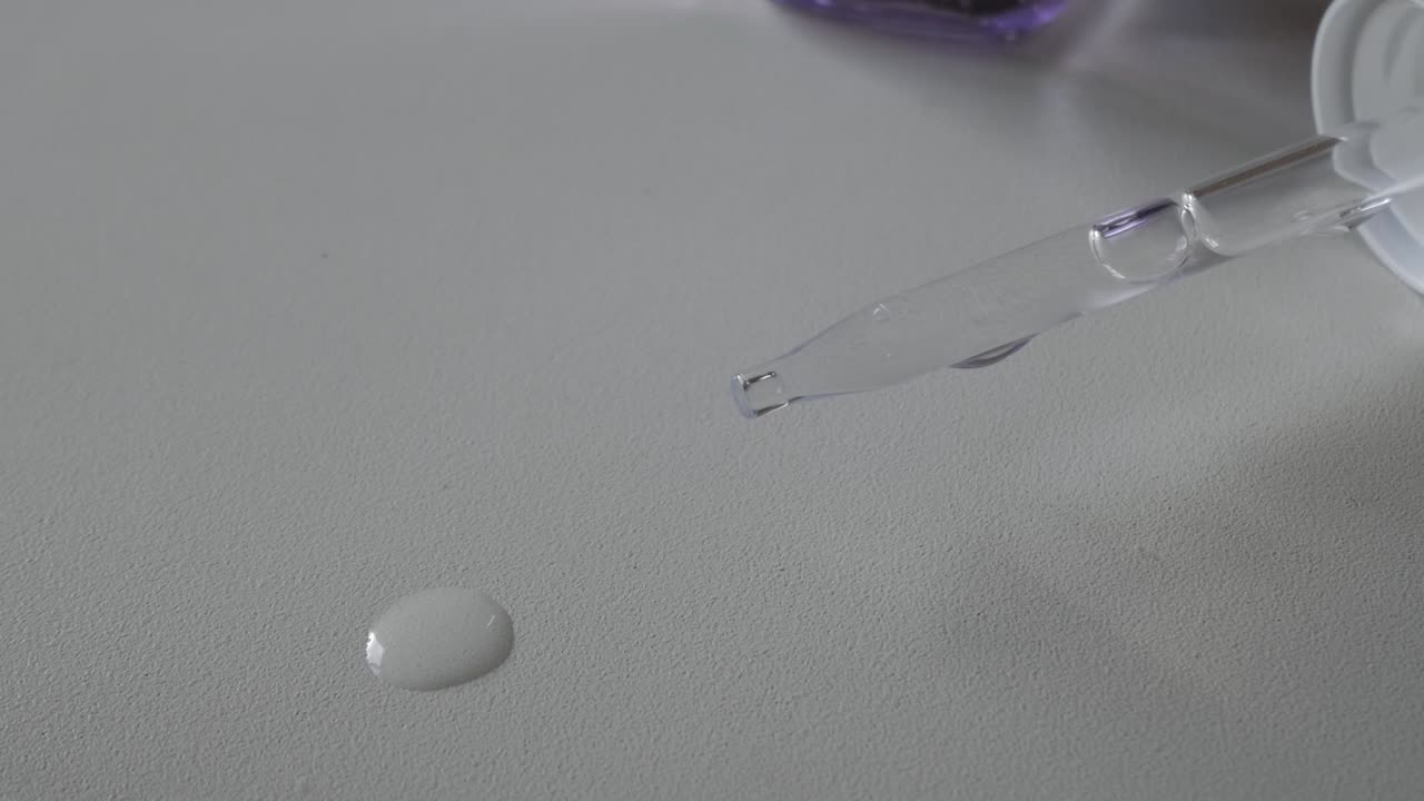 Drop of hyaluronic acid and retinol serum on a smooth surface, close-up shot