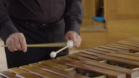 close up man in smart black shirt playing xylophone in concert hall