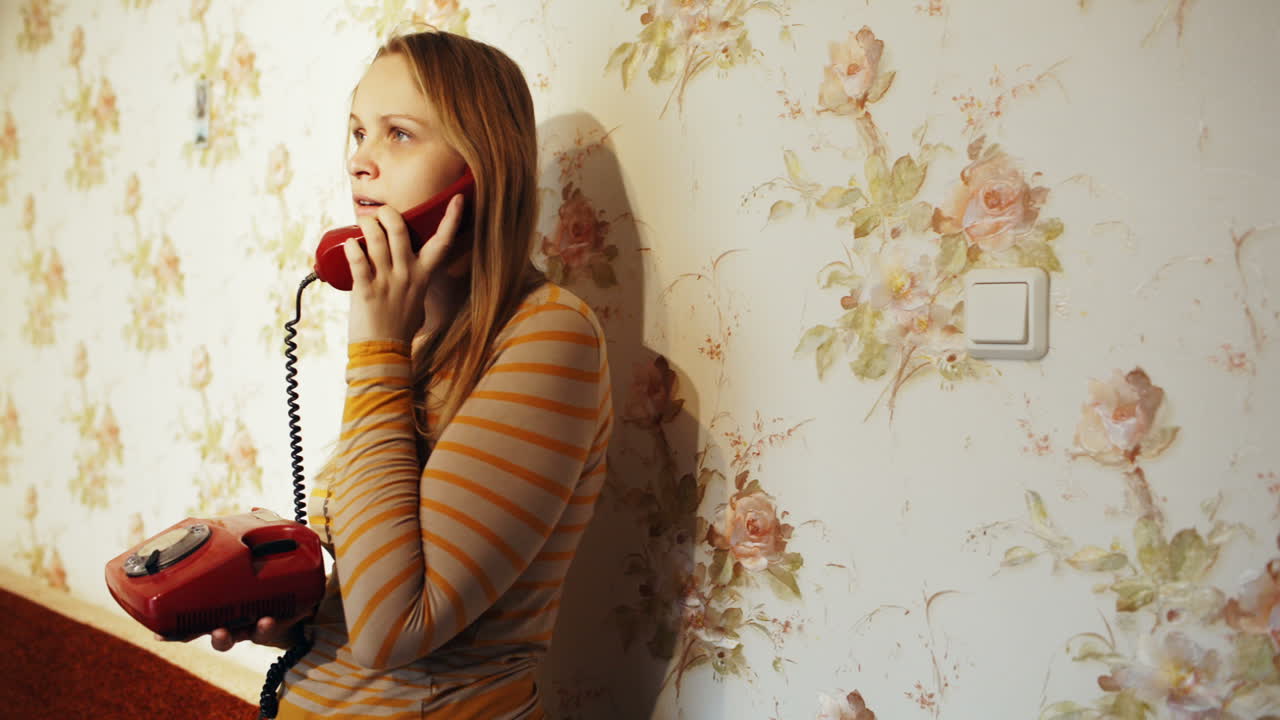 Ung kvinde taler i telefon derhjemme