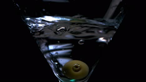 olive in a martini glass with splashing water