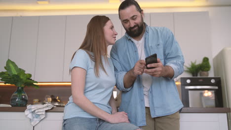 bearded man showing mobile phone photos to an attractive woman