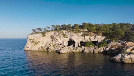 Aerial---calm-turquoise-water-lagoon-near-ancient-cave-system,-Mallorca