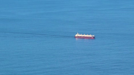 Slow-Pan-of-Cargo-Ship-on-Blue-Ocean-In-Distance