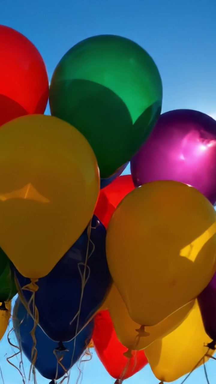 Una Vivace Esposizione di Palloncini Colorati che Ascendono Contro un Cielo Azzurro Brillante, Catturando l'Essenza del Divertimento e della Celebrazione Sotto un Sole Radioso