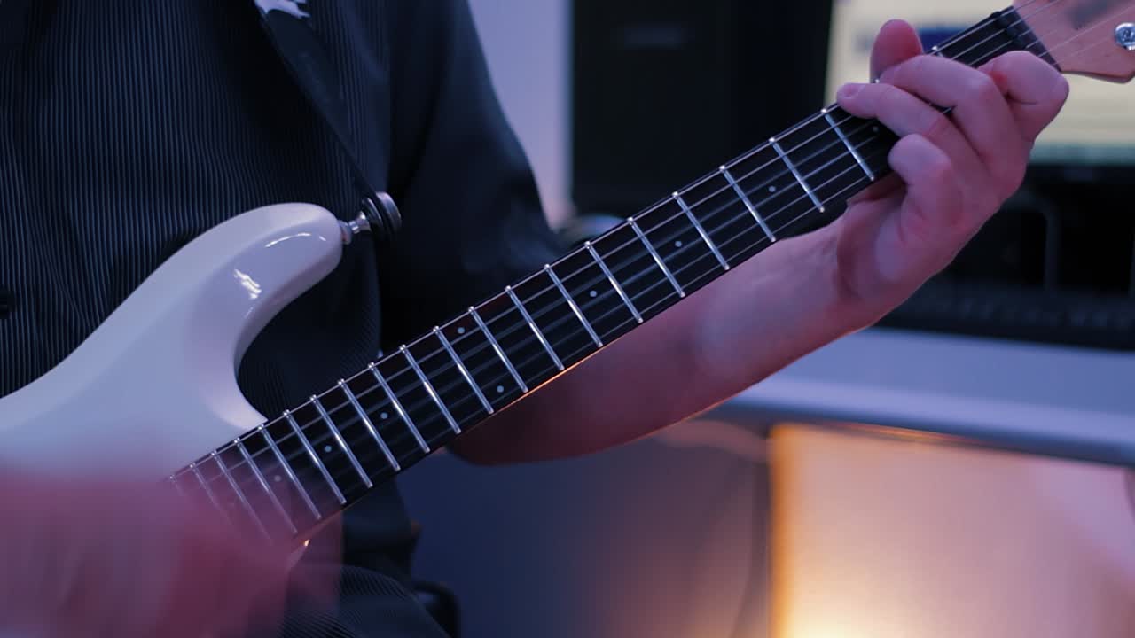 Stüdyoda gitar çalan olgun bir adam.