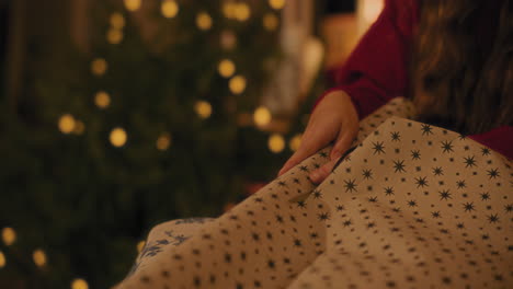 Woman-cutting-paper-while-wrapping-Christmas-gift