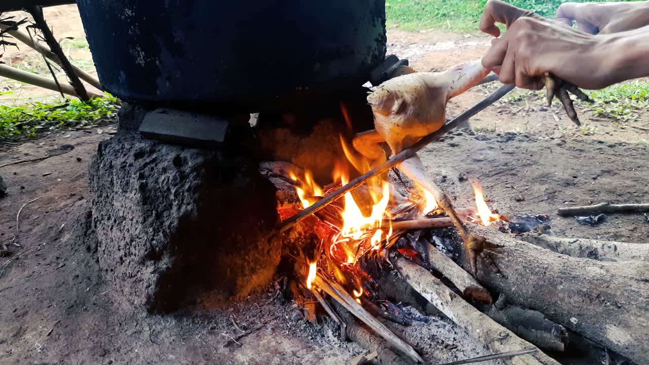 manos asando pollo sobre fogata. estático, ángulo alto