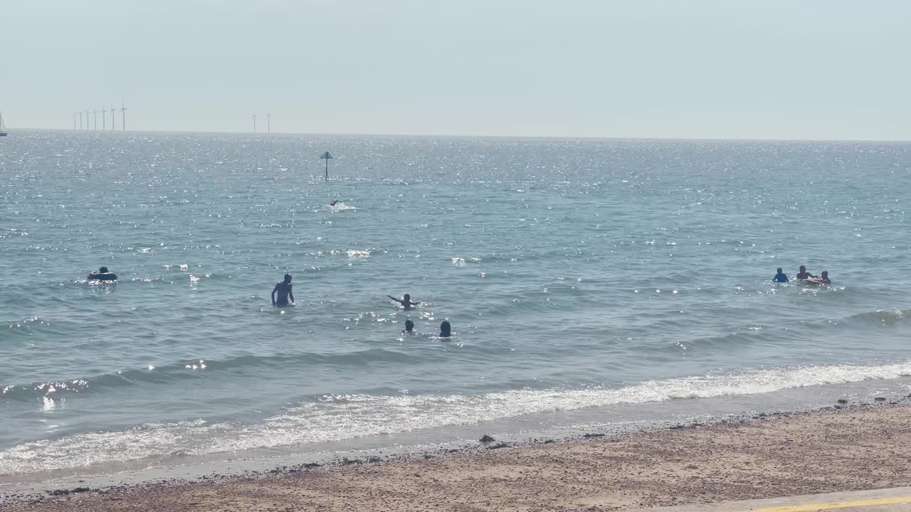 영국 에식스주 클락턴 온 시에 있는 해변에서 화창한 날씨를 즐기는 사람들