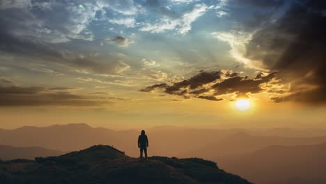 the man standing on a mountain top against the bright sunset. time lapse