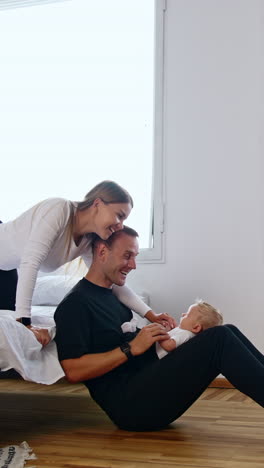 caring parents spend time with their cute tiny kid. man and woman talk to baby and smile happily. vertical video