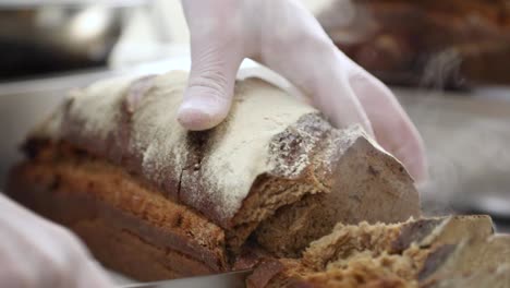 Hand-Des-Konditors-In-Handschuhen,-Die-Heißes-Und-Frisch-Gebackenes-Brot-Schneiden