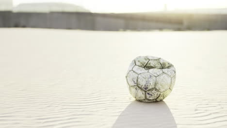 lost and weathered soccer ball on a sandy beach at sunset
