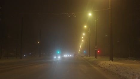 Late-night-drive-on-snow-covered-slippery-roads-in-city,-pov