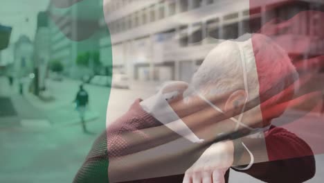 animation of flag of italy waving over caucasian man wearing face mask