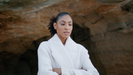 modelo de cabello negro posando en la roca de la cueva de la orilla del mar. hermosa mujer pensativa contemplando