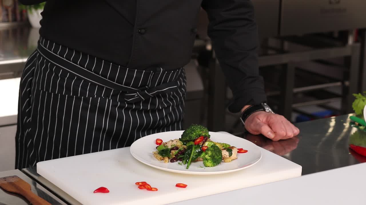 Chef Seasoning a Plate of Pasta with Broccoli