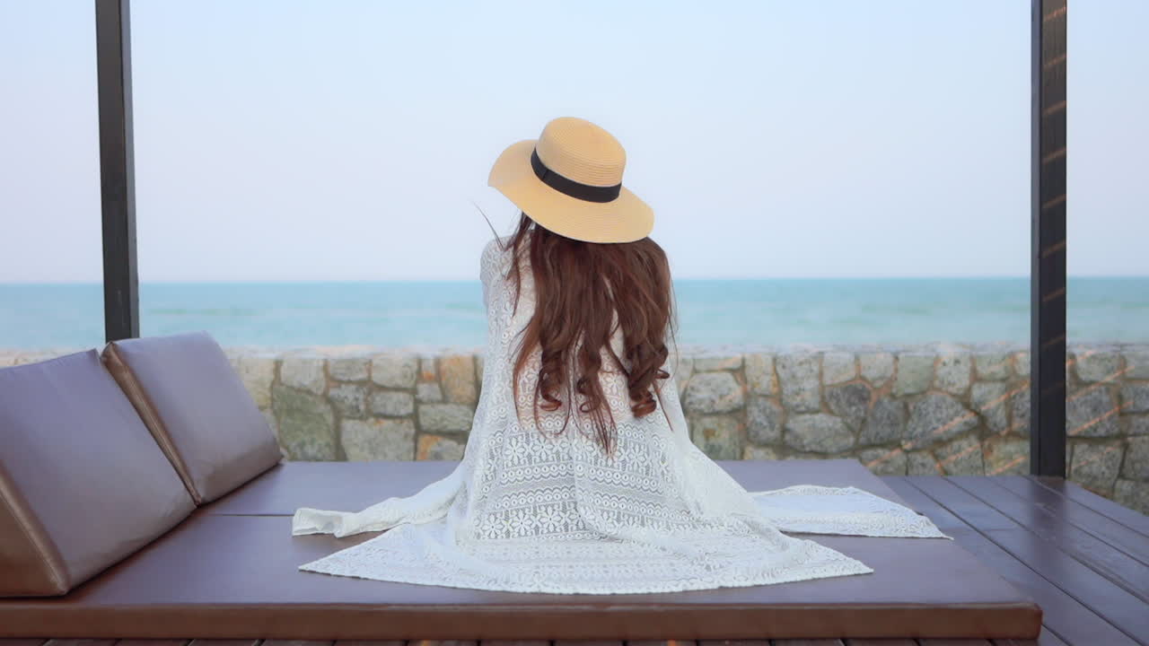 Young beautiful women sitting and relaxing on the beachside resort with a beautiful view of the endless ocean