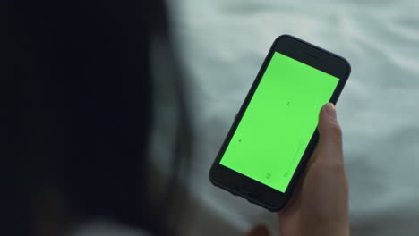 Woman-touching-smartphone-with-green-screen.-Woman-hand-holding-mobile