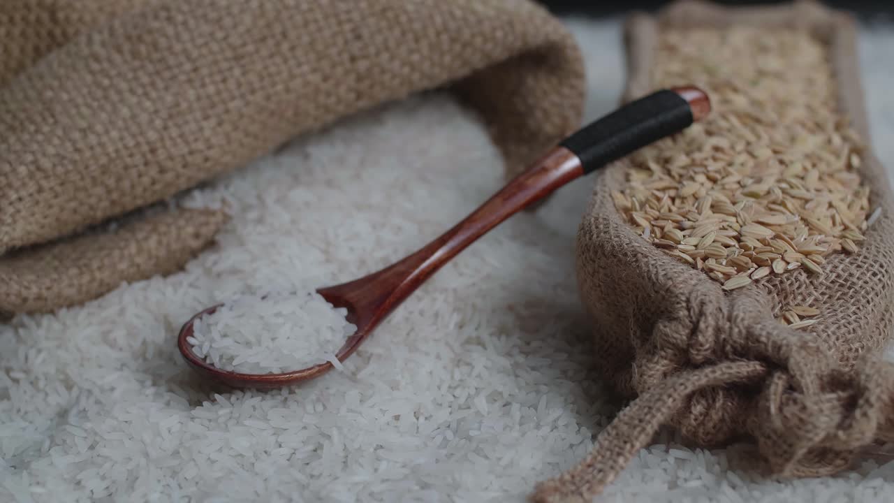 Raw Rice Grain In Wooden Bowl, Rustic Bag And Spoon Rotate In Slow Motion. Main Asian Food