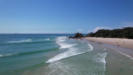 blue ocean waves splashing sandy shore in clarkes beach, new south wales, australia - drone shot