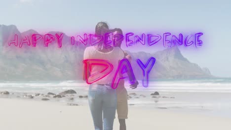 animation of text independence day over african american couple dancing at beach