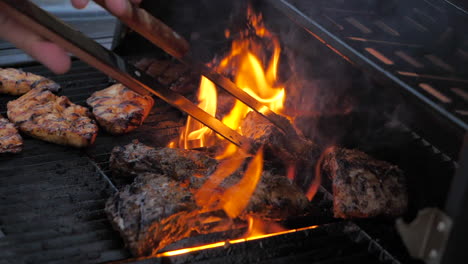 barbecue chef putting meat in the flames on grill with cooking pliers