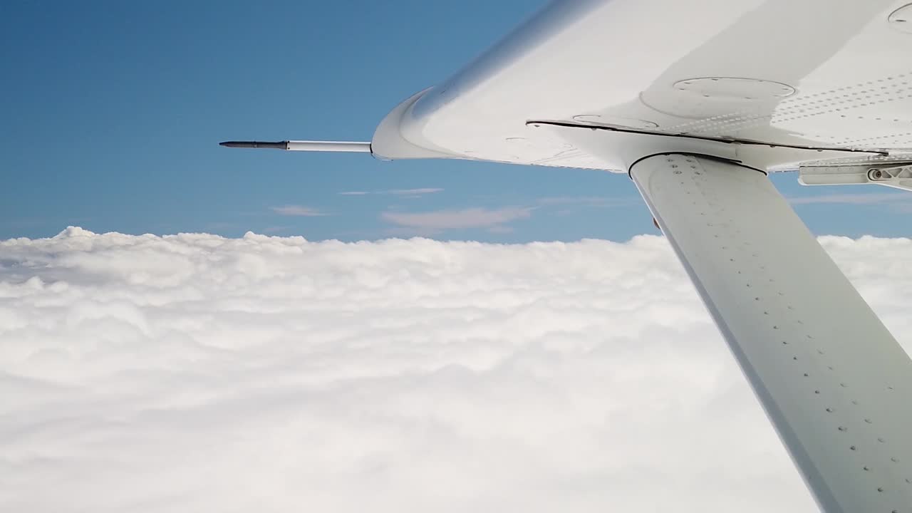 두꺼운 흰 구름 위를 비행하는 작은 비행기의 날개 끝을 자세히 보기