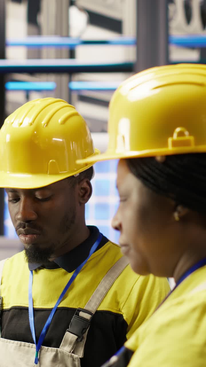 Vertical video Manager supervising technician in factory using PC to diagnose malfunctions