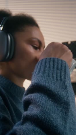 woman working from home, drinking coffee and wearing headphones.