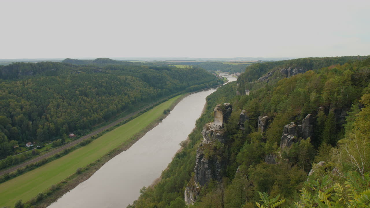 Sachsen Elbsandsteingebirge Elbe sandstone formations rising above dense green forests Mountains, under a blue sky with scattered clouds, showcasing the region’s natural beauty and rugged Terrain