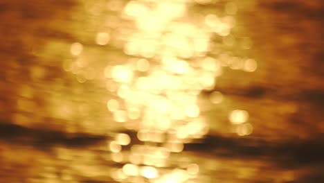 bokeh sun glare reflection of sunset sunrise light in water surface. sunrays flickering in ocean.golden shimmering sea waves in sun abstract blurry out of focus bokeh amazing autumn background