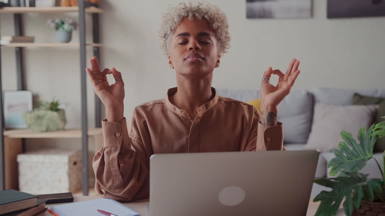Serene african woman relieving fatigue at workplace make meditation practice