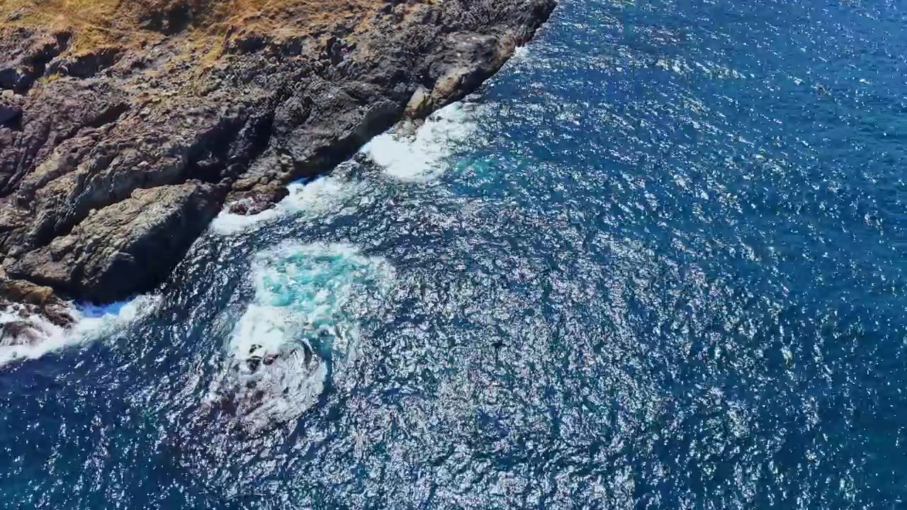 Litoral encontra o oceano em um dia claro e ensolarado com água cristalina e costa rochosa.