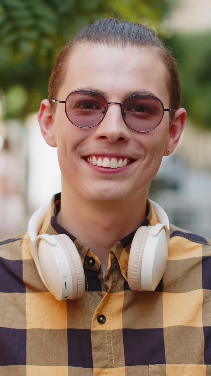 Portrait of happy man with headphones around neck smiling friendly glad expression looking at camera