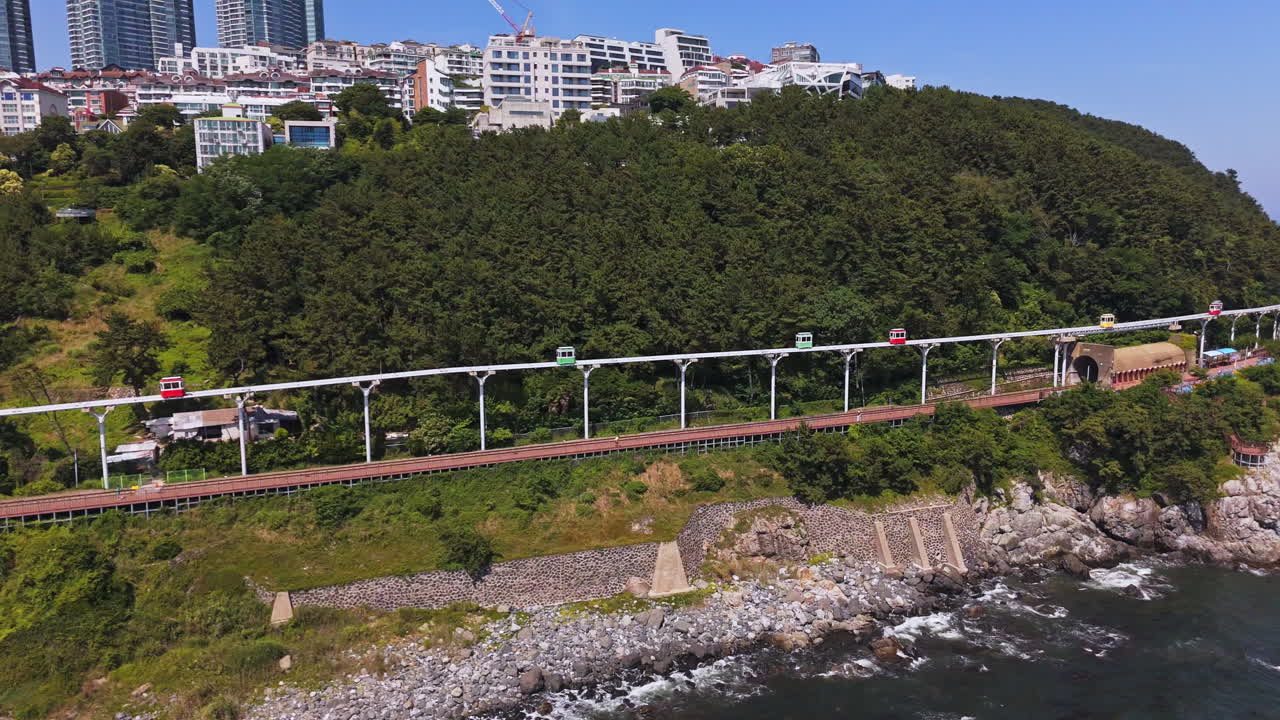 Drone flying along the Haeundae Sky Capsule rail in sunny Busan, South Korea