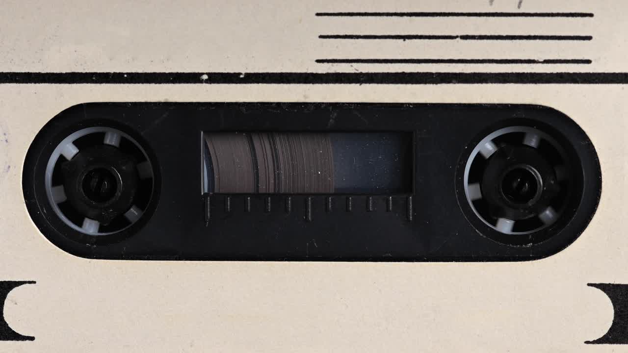 Close-up A tape recorder is playing an audio cassette. Close-up. A vintage audio cassette spins on a blank label tape used to record sound in a retro cassette player. Recording of conversations.