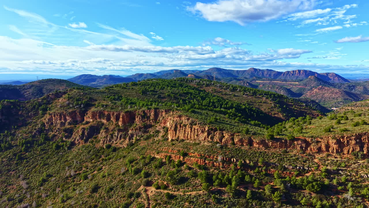 Vedute di un paesaggio montano in una zona remota di giorno, con cielo e nuvole sopra e alberi e rocce in primo piano.
