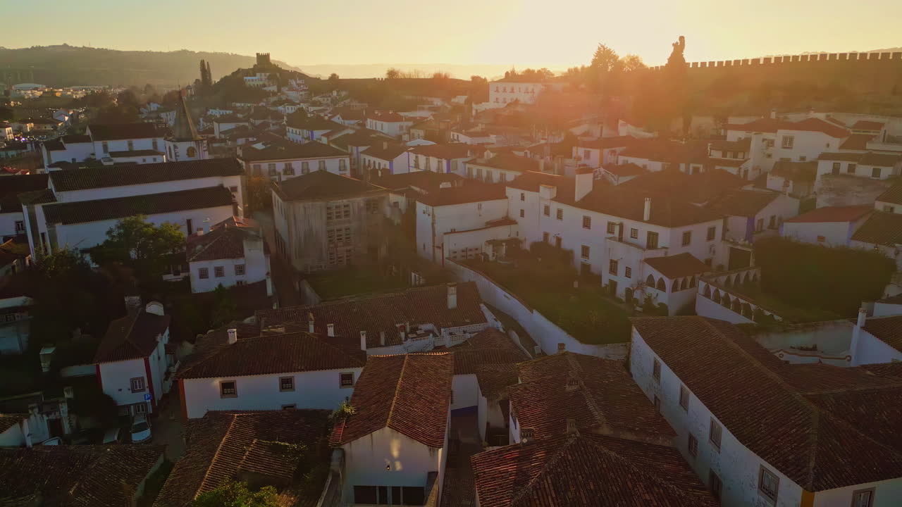 Drone cozy town suburb with red tiled rooftops at sunset. Historic village