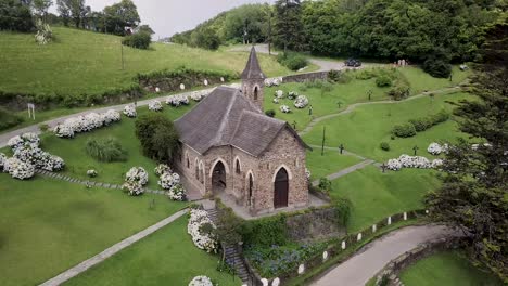 aerial view crossing roof of villa nogues rural little stone church with slate roof, moving closer to tower spire