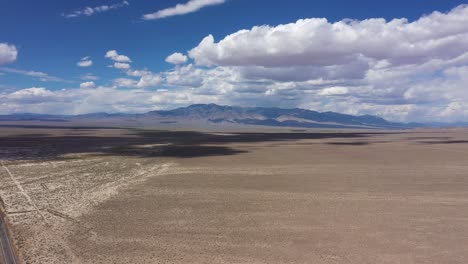 Slow-moving-clouds-and-shadows-drifting-across-the-Nevada-desert-with-blue-skies-and-mountains-in-the-distance