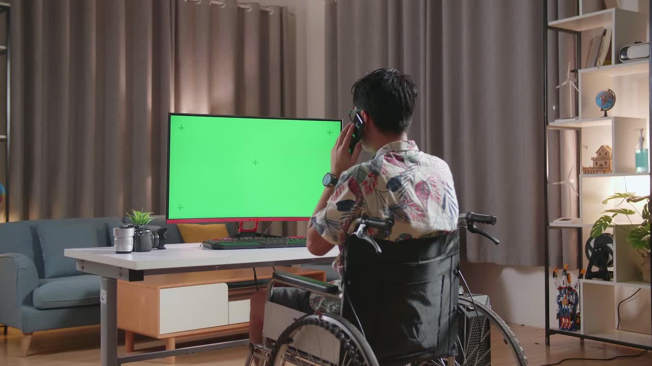 체어 에 앉은 사람 이 녹색 화면 모니터 를 가진 집 사무실 에서 전화 로 이야기 하고 있다