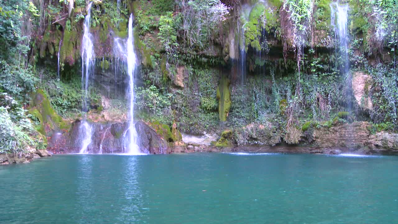 무성하고 비옥한 열대 폭포가 녹색 수영장으로 흘러 들어갑니다