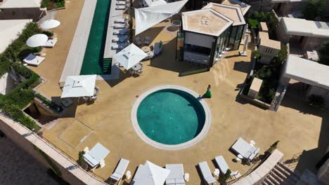 female guest walking at pool area of mamula island hotel in summer. historic fortress in mamula, montenegro. aerial tilt-down shot