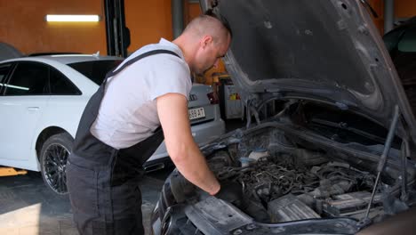 mechanic working on a car engine in an auto service garage